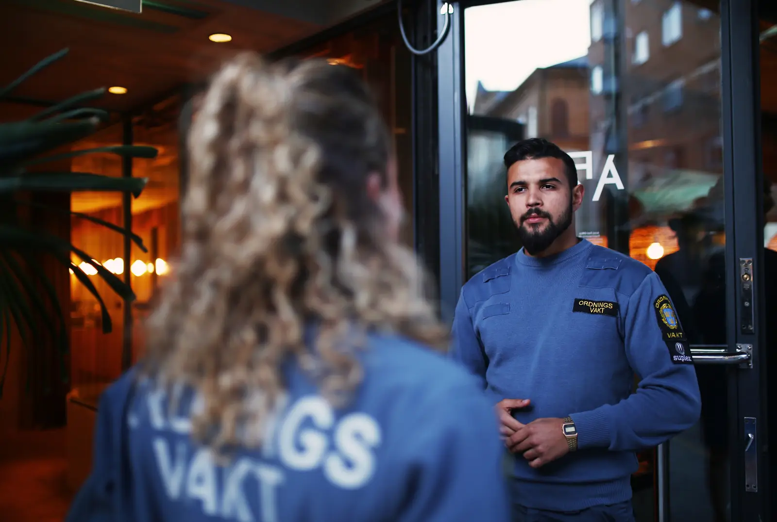 Två uniformerade ordningsvakter tar emot gäster vid en entré